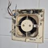 Before Faulty white plastic extractor fan on a white tiled bathroom wall before being removed for a clean modern replacement job