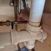 Progress view inside a kitchen cupboard tightening valves under the sink for a tap installation at Morgan House near Riverside