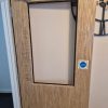 Fire door frame with its damaged glass pane stripped out and cleared during an indoor property maintenance repair project