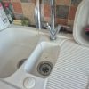 Close up of a leaking chrome mono mixer tap dripping water drops into a porcelain utility room sink on a job in Spixworth