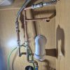 Finished under sink plumbing showcasing new copper pipework and flexible hoses routed to feed a brand new garden outdoor tap