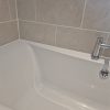 Freshly applied bright white waterproof silicone sealant creating a clean straight line along a bathtub edge