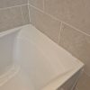 Old discoloured bathroom silicone sealant on a bathtub edge with dark mold spots and visible signs of water damage