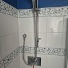 Brand new chrome shower head and polished flexible stainless steel hose cleanly fitted on a bathroom riser rail wall